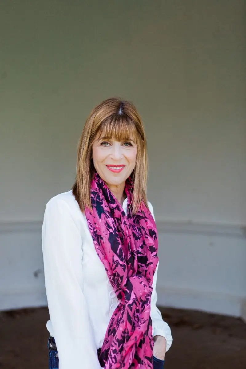 Dr Annie Kaszina in a white blouse and pink scarf, looking warmly at the camera